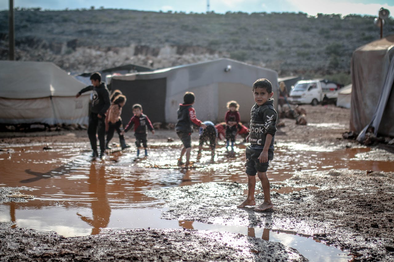 Children enjoy playing in muddy puddles at a refugee camp in Idlib, Syria.